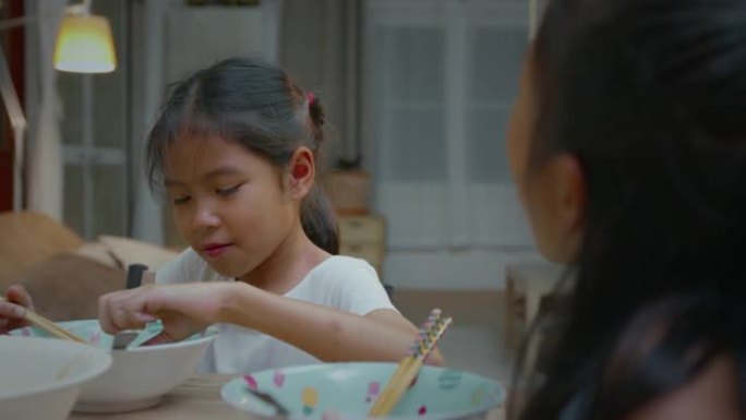 两名亚裔少女兄妹吃着泡面，在家里共享晚餐，幸福有加。