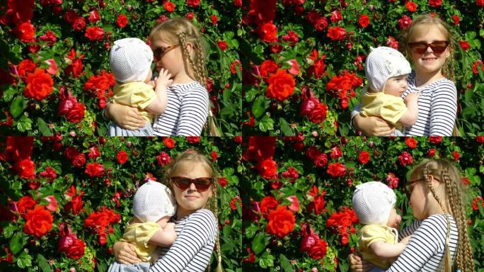在玫瑰背景下的花园里怀抱婴儿的女孩