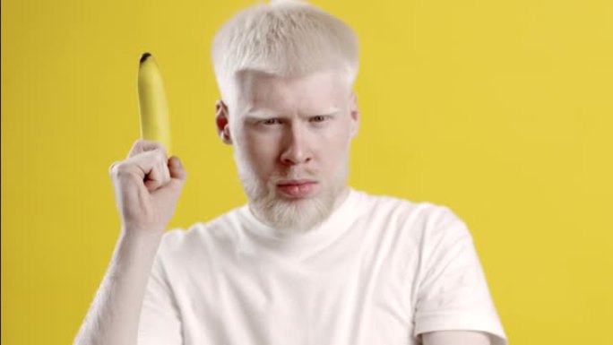 白化病男与香蕉假扮射击枪，黄色背景