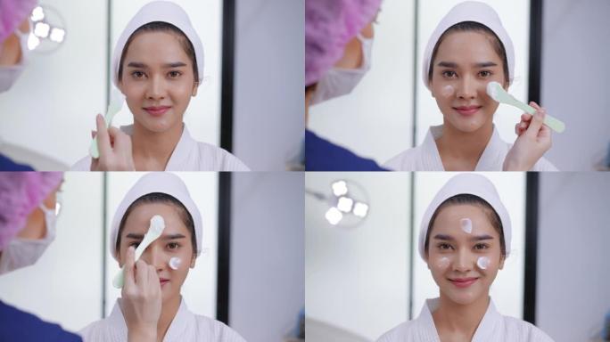 头部镜头: 幸福的微笑医疗患者，戴着卫生发帽的女医生开始为接受润肤霜的年轻亚洲女性提供面部护理服务，