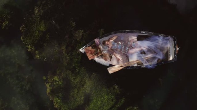 美丽公主女人在划艇中放松的幻想角色扮演概念 -- 头顶空中无人机顶部