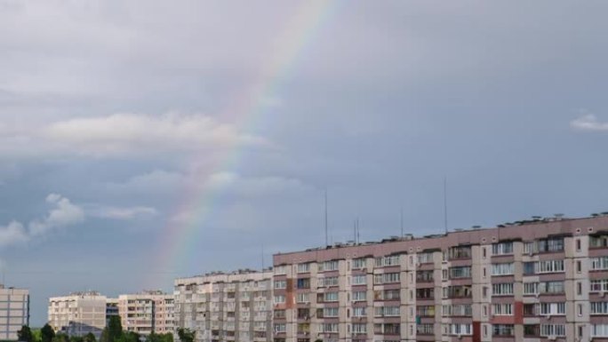 城市房屋上方多云天空中的巨大彩虹，延时