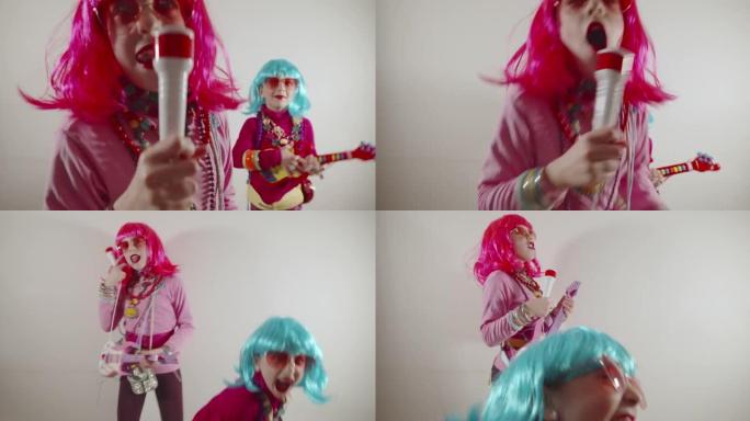有趣可爱的快乐小女孩播放器吉他和麦克风唱歌，穿着五颜六色的流行套装，如太阳镜和五颜六色的假发