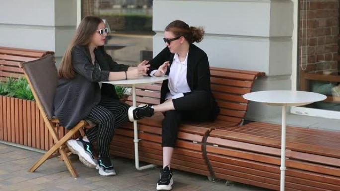 女友坐在街头咖啡馆的长椅上交流