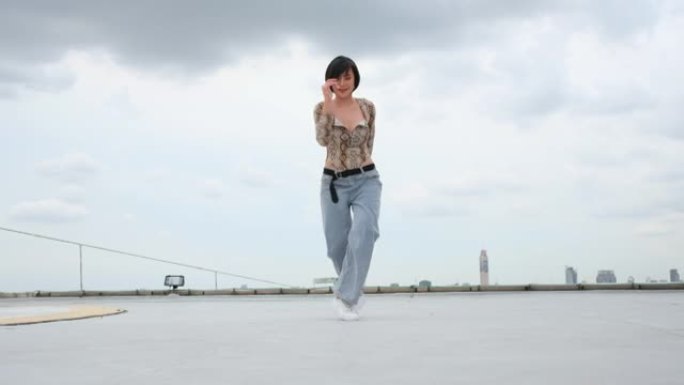 亚洲妇女在以大城市或城市景观为背景的高楼露台或屋顶上表演舞蹈