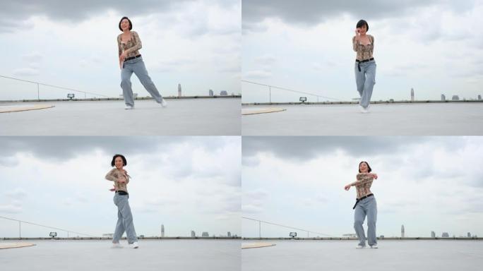 亚洲妇女在以大城市或城市景观为背景的高楼露台或屋顶上表演舞蹈