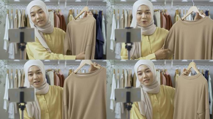 年轻美丽的亚洲女人正在她的服装店直播。她与顾客交谈并解释她的产品。