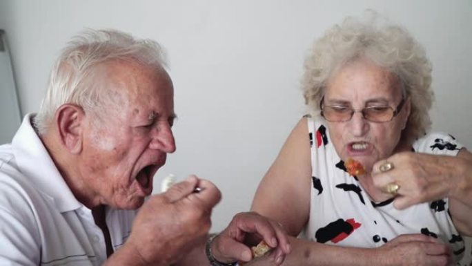 开朗的高级夫妇在家与健康食品一起吃饭。老年快乐的老年夫妇在家中与健康食品一起饮食的健康营养概念。老年