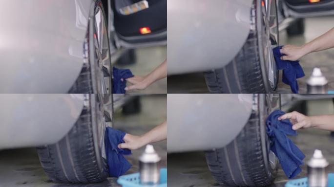 工人使用超细纤维毛巾清洁汽车轮胎和轮毂盖。