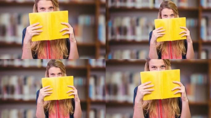 高加索女大学生在图书馆用书遮住脸