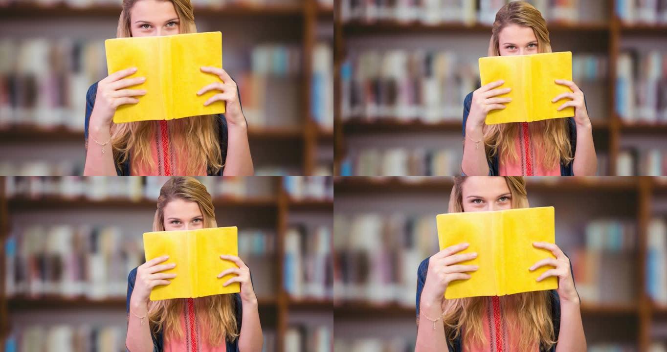高加索女大学生在图书馆用书遮住脸