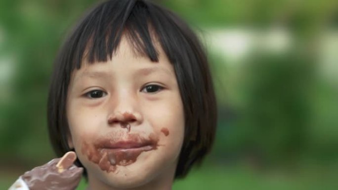 快乐微笑的亚洲儿童女孩乱吃巧克力冰淇淋。