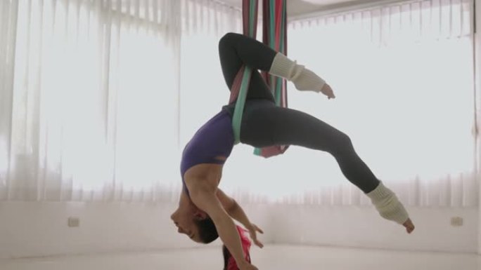 年轻女子做颠倒反重力瑜伽和抓一条腿-股票视频