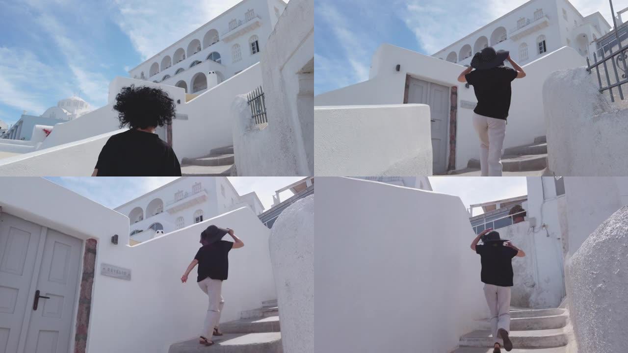 年轻女子在希腊圣托里尼岛菲拉市的楼梯上奔跑，慢动作