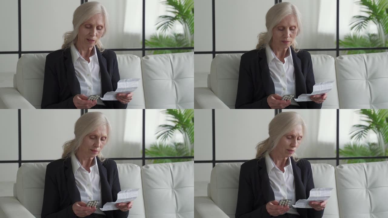 白发苍苍的老妇在家服药前先阅读说明书。祖母坐在沙发上阅读平板电脑的使用说明