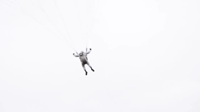 一名跳伞者带着机翼降落伞在空中盘旋的后视图。行动。专业的天空潜水员在灰色多云的天空背景上飞行时拉动吊