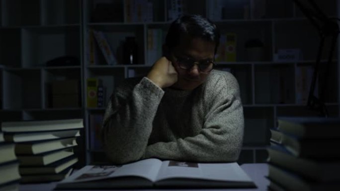 年轻人坐在昏暗的图书馆里看书