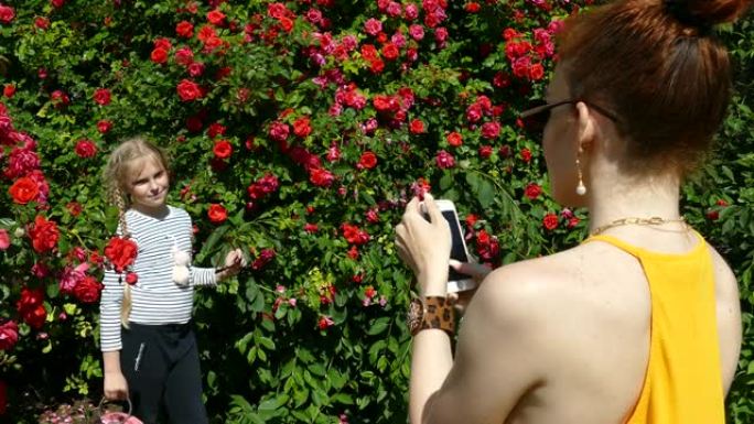 女人教一个女孩在玫瑰园摆姿势拍照
