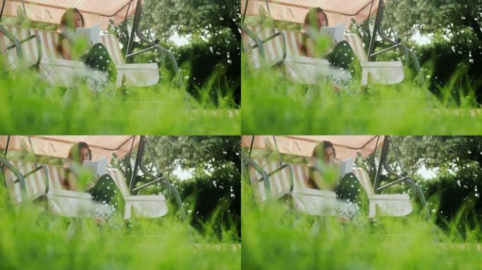 一个女人坐在秋千上的电影镜头在花园里看书