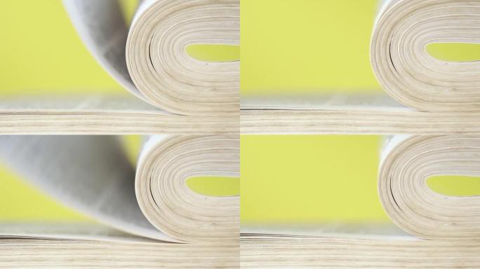 一本书的书页在慢动作中落下和翻身。在明亮的黄色背景上