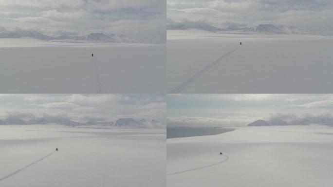 在斯瓦尔巴群岛的雪地摩托上，无人驾驶飞机拍摄了男子