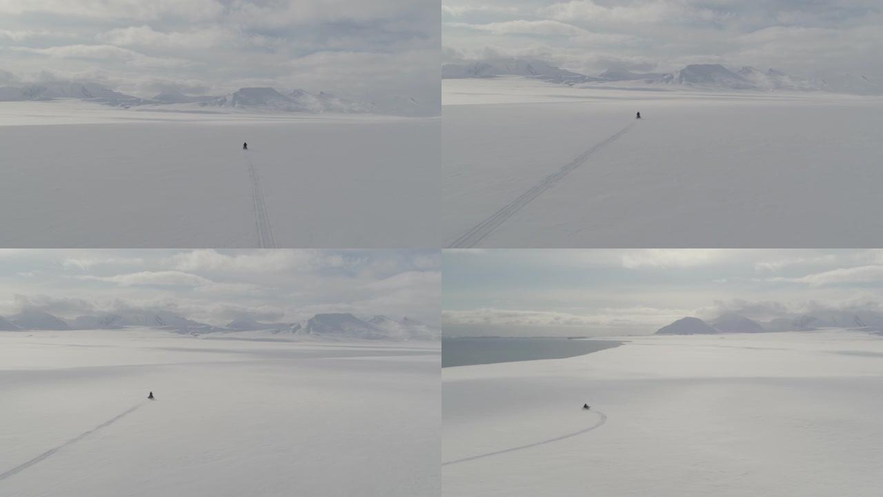 在斯瓦尔巴群岛的雪地摩托上，无人驾驶飞机拍摄了男子