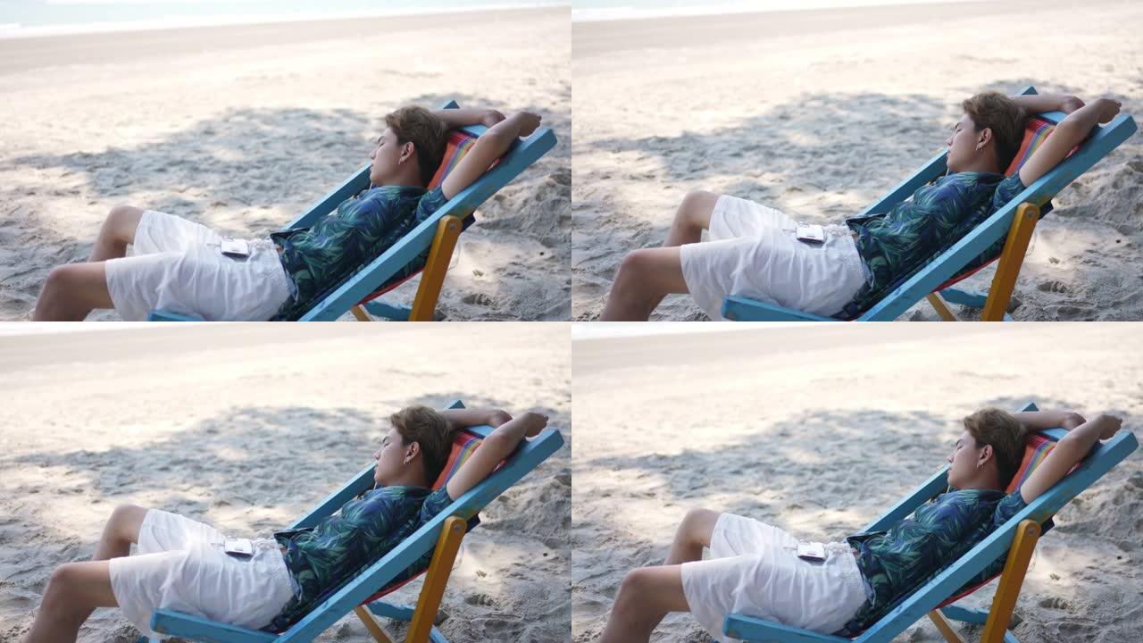 夏天阳光明媚的日子，亚洲人睡在沙滩上的沙滩椅上。