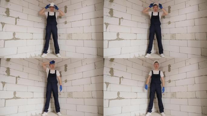 一个戴着白色安全帽的疲惫的建筑工人正站在一间新公寓里。