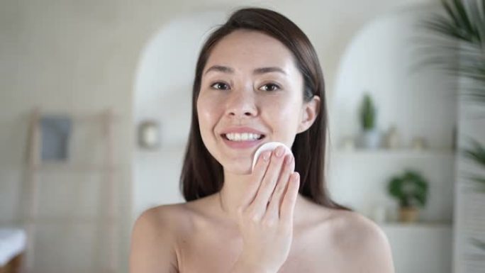 迷人的年轻多民族女性沐浴后清洁皮肤和毛孔保持棉垫使用凝胶双相洁面乳去除化妆和污垢享受有效的美容护理化
