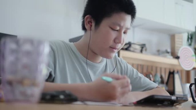 亚洲男孩在新型冠状病毒肺炎期间通过智能手机学习在线课程，检疫生活方式概念。