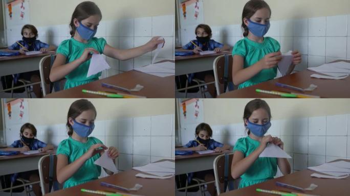 女学生在教室里折叠纸。新型冠状病毒肺炎概念