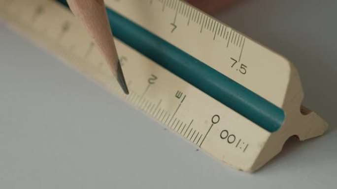 特写镜头，男性双手用三角尺子用木笔放在白纸上，用绘图工具。