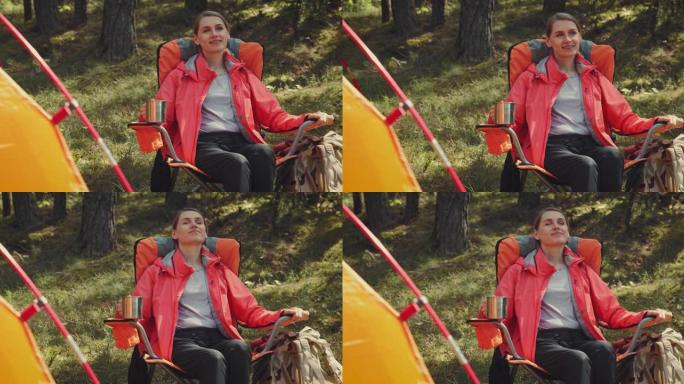快乐的女人在森林营地的野营椅上休息时享受大自然。户外冒险
