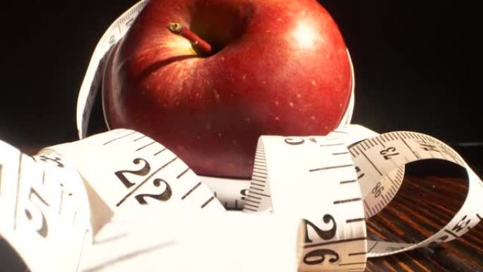 用卷尺包裹的红苹果。饮食，健康饮食，减肥理念