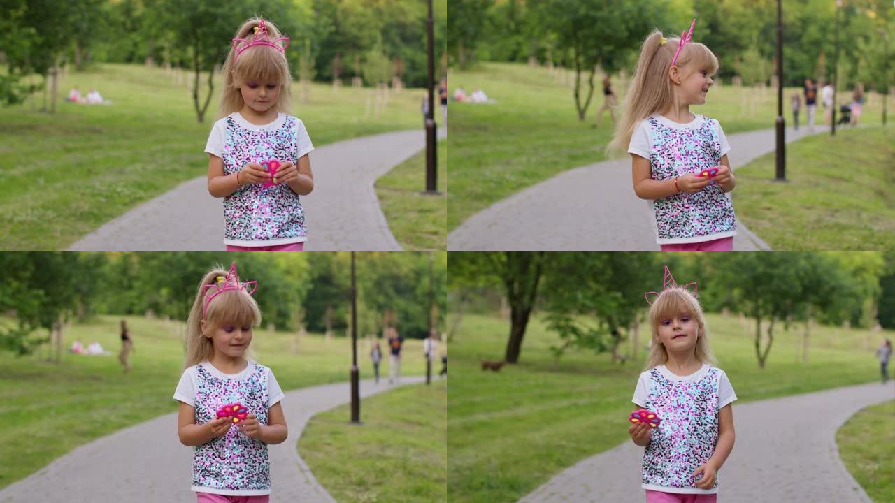 女孩在公园散步时玩流行音乐感觉抗压力手旋转器软软泡泡玩具