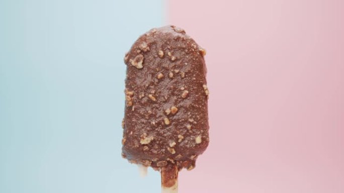 融化的巧克力冰淇淋棒孤立在蓝色粉色背景上。