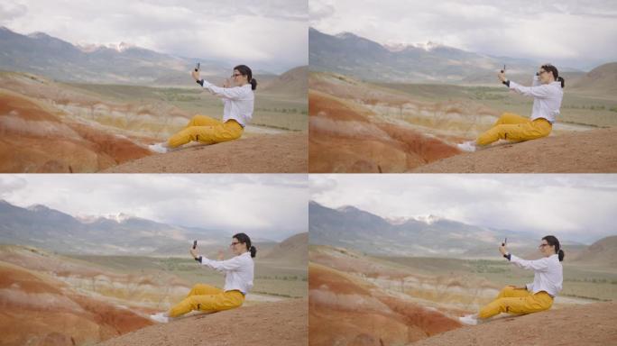 博客作者坐在山崖边的智能手机相机上自拍