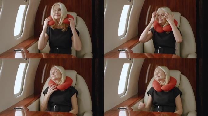 美丽富有的成熟女人在一流的商务舱航空公司奢华旅行时使用颈枕。