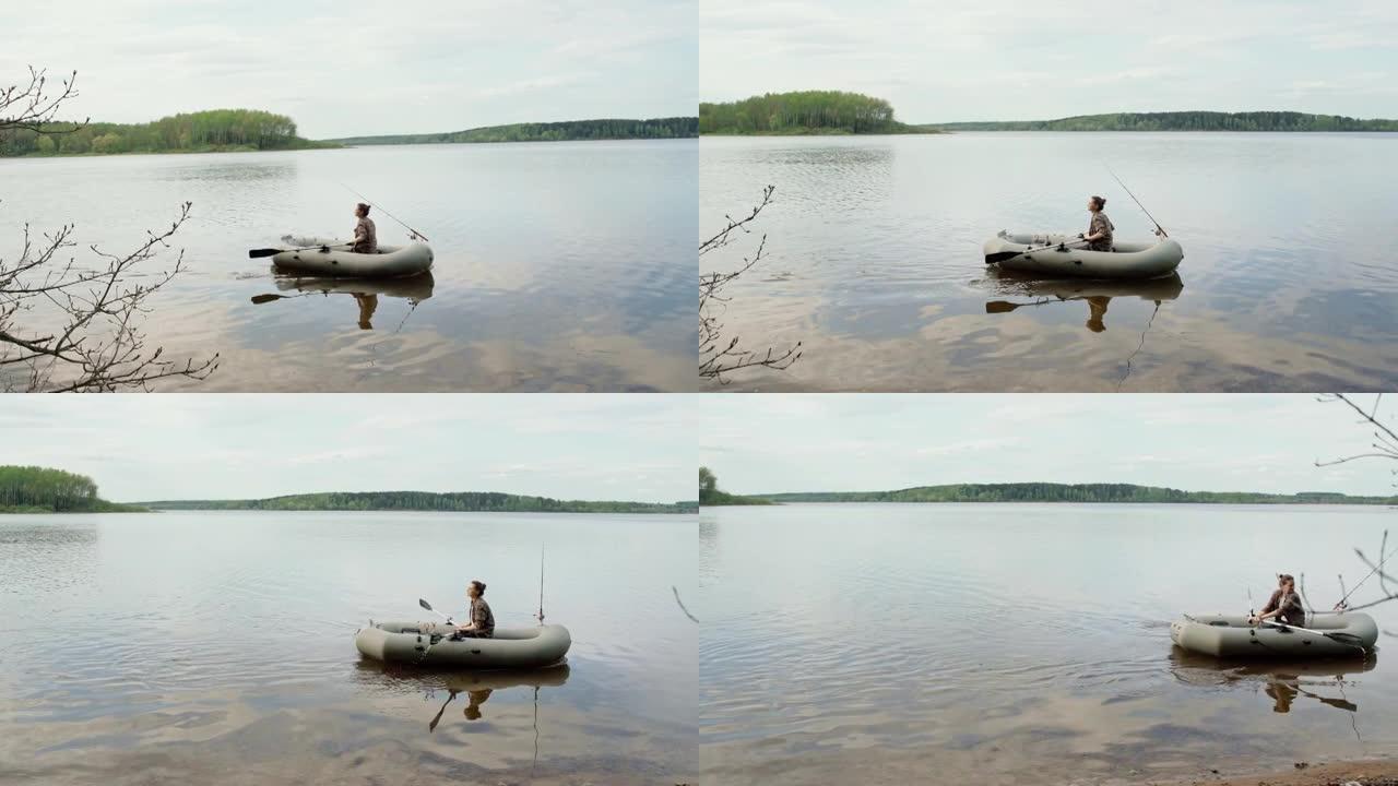年轻的渔民在湖上的充气船上划桨。