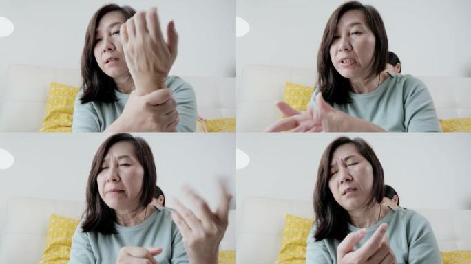 亚洲母亲视频电话给医生和按摩自己在新型冠状病毒肺炎期间在家疼痛和疼痛，检疫的生活方式概念。