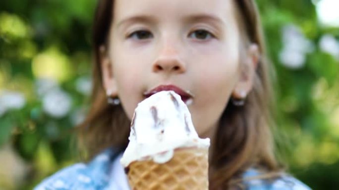 可爱的女孩在夏天在公园休息时吃意大利冰淇淋蛋卷微笑