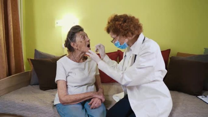 一名老年妇女正在家里接受冠状病毒测试。一位穿着实验室外套的医生在疗养院的喉咙高级女性身上拭子了cov