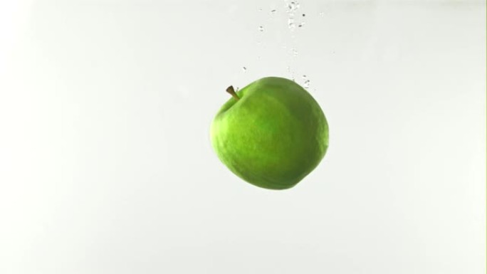 超级慢动作新鲜苹果落在有气泡的水下。以1000 fps的高速相机拍摄。