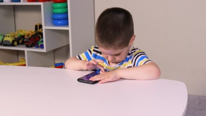 一个3-4岁的小男孩看着手机屏幕。