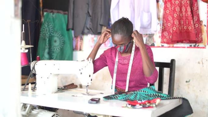 非洲女裁缝坐在缝纫机上戴上口罩
