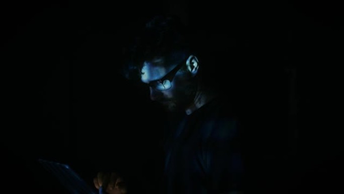 男人通过蓝色数字光使用平板电脑