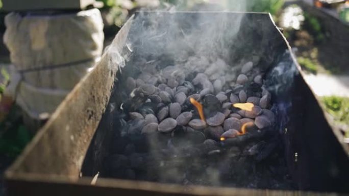 在烤架上吸烟木炭的慢动作镜头。肉很快就会在这里煮熟