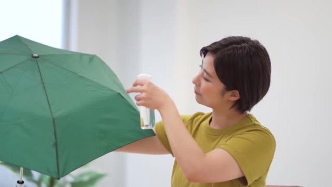一名妇女在折叠伞上喷洒防水喷雾