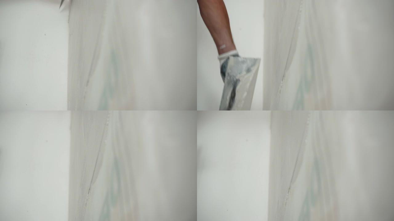 施工现场维修工程，工程工人戴着防护手套，用金属刮铲打墙，用白色涂抹膏溶液平整和对准墙面。墙壁粉饰工艺