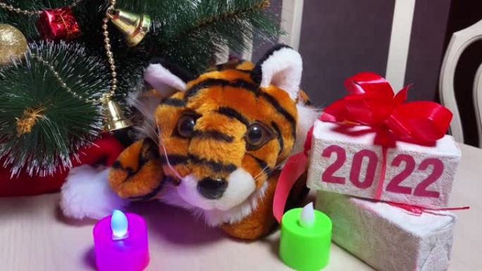 老虎符号2022年年份，蜡烛和礼品盒，白色桌子上有文字2022，房间里有新年树。
